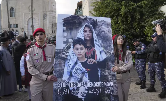 Palestinian scouts carry a poster while they march during Christmas Eve celebrations at the Church of the Nativity, traditionally recognized by Christians to be the birthplace of Jesus Christ, in the West Bank city of Bethlehem Tuesday, Dec. 24, 2024. (AP Photo/Nasser Nasser)