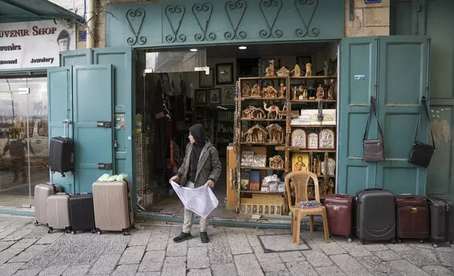 A boy waits outside a souvenir shop near the Church of the Nativity, where Christians believe Jesus Christ was born, ahead of Christmas in the West Bank city of Bethlehem, Saturday Dec. 21, 2024. (AP Photo/Mahmoud Illean)