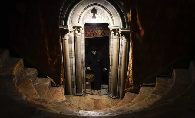 A worshipper cleans candles from altars in the Church of the Nativity, where Christians believe Jesus Christ was born, ahead of Christmas in the West Bank city of Bethlehem, Monday, Dec. 23, 2024. (AP Photo/Matias Delacroix)