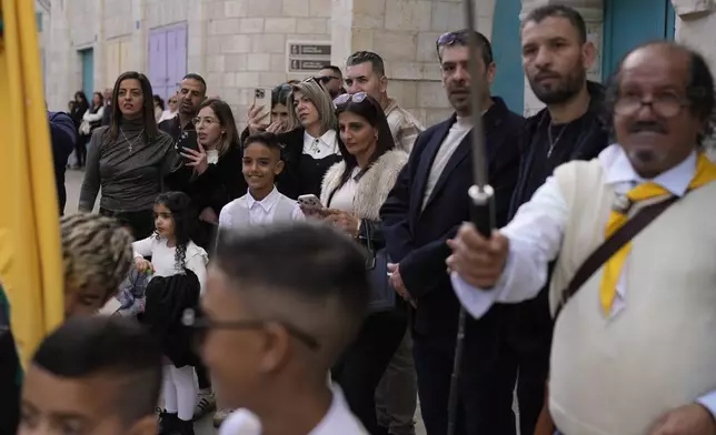 People watch the traditional Christian procession towards the Church of the Nativity, traditionally believed to be the birthplace of Jesus, on Christmas Eve, in the West Bank city of Bethlehem, Tuesday, Dec. 24, 2024. (AP Photo/Matias Delacroix)