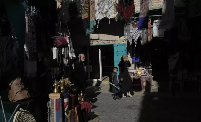 People walk through an alley near the Church of the Nativity, traditionally believed to be the birthplace of Jesus, on Christmas Eve, in the West Bank city of Bethlehem, Tuesday, Dec. 24, 2024. (AP Photo/Matias Delacroix)