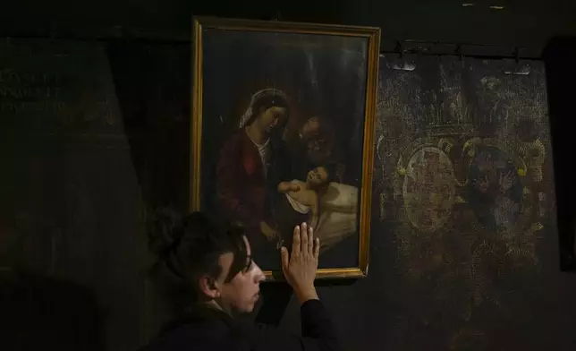 A worshipper touches a painting of Maria with Jesus Christ in the Church of the Nativity, where Christians believe Jesus Christ was born, ahead of Christmas in the West Bank city of Bethlehem, Monday, Dec. 23, 2024. (AP Photo/Matias Delacroix)