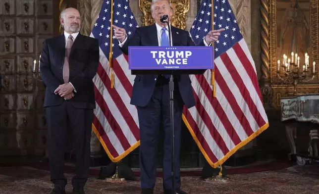 President-elect Donald Trump speaks during a news conference at Mar-a-Lago, Monday, Dec. 16, 2024, in Palm Beach, Fla., as Commerce Secretary nominee Howard Lutnick listens. (AP Photo/Evan Vucci)