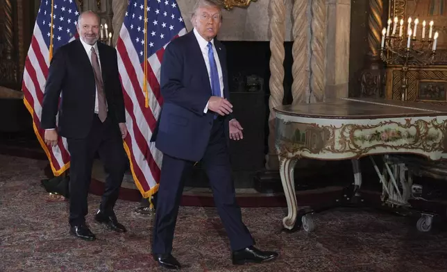 President-elect Donald Trump departs a news conference at Mar-a-Lago, Monday, Dec. 16, 2024, in Palm Beach, Fla., followed by Commerce Secretary nominee Howard Lutnick. (AP Photo/Evan Vucci)