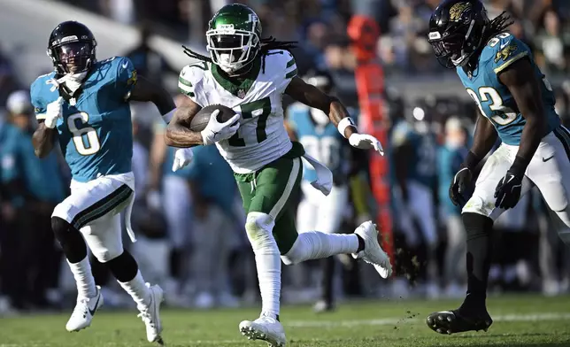 New York Jets wide receiver Davante Adams (17) gets between Jacksonville Jaguars safety Darnell Savage (6) and linebacker Devin Lloyd (33) tomscore on a 71-yard touchdown reception during the second half of an NFL football game Sunday, Dec. 15, 2024, in Jacksonville, Fla. (AP Photo/Phelan M. Ebenhack)