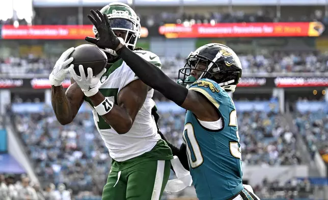 New York Jets wide receiver Davante Adams (17) catches a 1-yard touchdown pass in front of Jacksonville Jaguars cornerback Montaric Brown (30) during the second half of an NFL football game Sunday, Dec. 15, 2024, in Jacksonville, Fla. (AP Photo/Phelan M. Ebenhack)