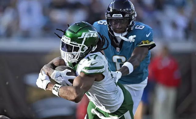 New York Jets wide receiver Davante Adams (17) scores ahead of Jacksonville Jaguars safety Darnell Savage (6) on a 71-yard touchdown reception during the second half of an NFL football game Sunday, Dec. 15, 2024, in Jacksonville, Fla. (AP Photo/Phelan M. Ebenhack)