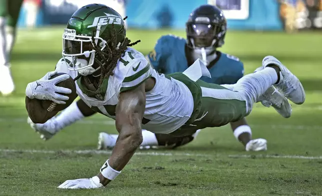 New York Jets wide receiver Davante Adams (17) dives past Jacksonville Jaguars safety Darnell Savage (6) after a catch during the second half of an NFL football game Sunday, Dec. 15, 2024, in Jacksonville, Fla. (AP Photo/Phelan M. Ebenhack)