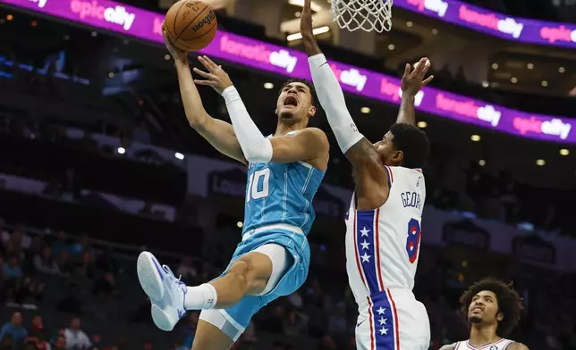 Charlotte Hornets guard Josh Green (10) drives to the basket against Philadelphia 76ers forward Paul George (8) during the first half of an NBA basketball game in Charlotte, N.C., Monday, Dec. 16, 2024. (AP Photo/Nell Redmond)