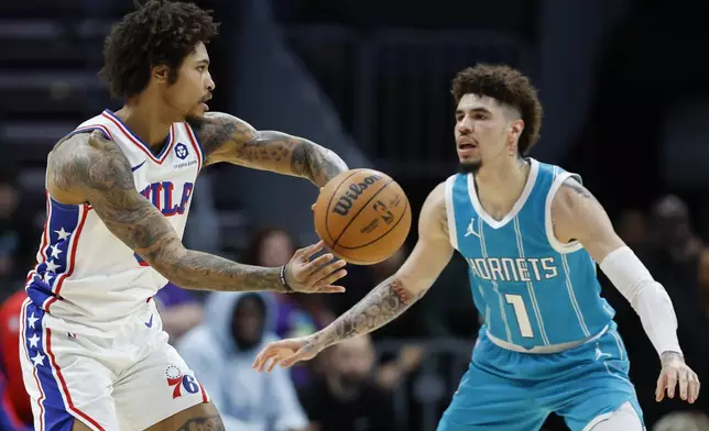 Philadelphia 76ers guard Kelly Oubre Jr., left, looks to pass the ball against Charlotte Hornets guard LaMelo Ball, right, during the first half of an NBA basketball game in Charlotte, N.C., Monday, Dec. 16, 2024. (AP Photo/Nell Redmond)