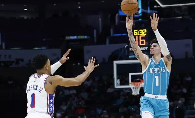 Charlotte Hornets guard LaMelo Ball, right, shoots over Philadelphia 76ers forward KJ Martin Jr., left, during the first half of an NBA basketball game in Charlotte, N.C., Monday, Dec. 16, 2024. (AP Photo/Nell Redmond)