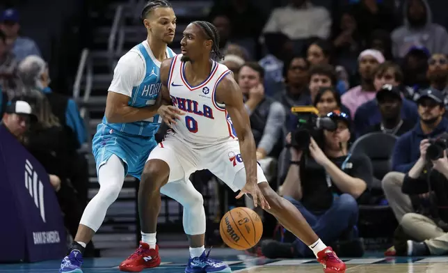 Philadelphia 76ers guard Tyrese Maxey (0) drives into Charlotte Hornets guard Isaiah Wong, left, during the first half of an NBA basketball game in Charlotte, N.C., Monday, Dec. 16, 2024. (AP Photo/Nell Redmond)