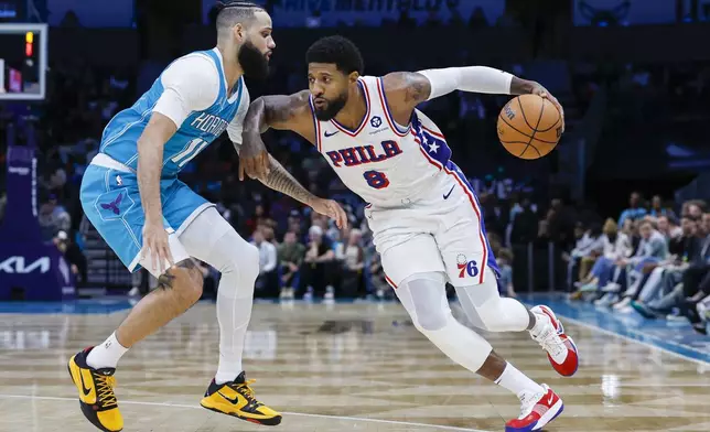 Philadelphia 76ers forward Paul George (8) drives against Charlotte Hornets forward Cody Martin, left, during the second half of an NBA basketball game in Charlotte, N.C., Monday, Dec. 16, 2024. (AP Photo/Nell Redmond)