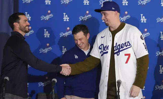 Los Angeles Dodgers pitcher Blake Snell, right, shakes hands with general manager Brandon Gomes, left, after putting on a jersey presented by president of baseball operations Andrew Friedman, center, during a news conference Tuesday, Dec. 3, 2024, in Los Angeles. (AP Photo/Jae C. Hong)