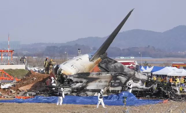 Firefighters and rescue team members work near the wreckage of a passenger plane at Muan International Airport in Muan, South Korea, Sunday, Dec. 29, 2024. (AP Photo/Ahn Young-joon)