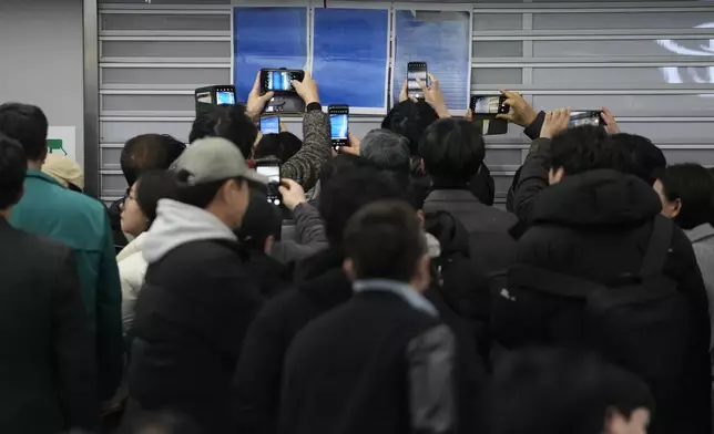 Relatives take photos of passenger lists at Muan International Airport in Muan, South Korea, Sunday, Dec. 29, 2024, after a passenger plane crashed at the airport. (AP Photo/Ahn Young-joon)