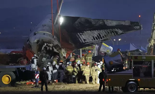 Rescue team carry the body of a passenger at the site of a plane fire at Muan International Airport in Muan, South Korea, Sunday, Dec. 29, 2024. (AP Photo/Ahn Young-joon)