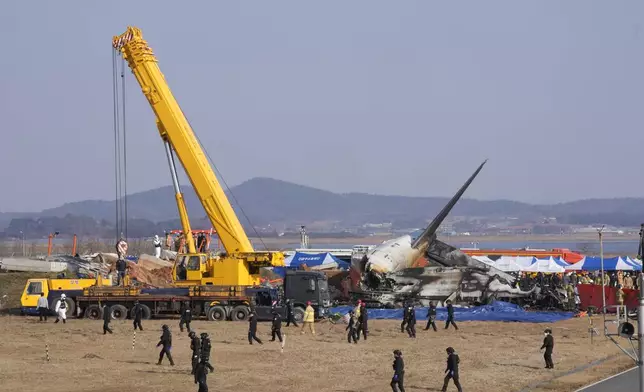 Firefighters and rescue team members work near the wreckage of a passenger plane at Muan International Airport in Muan, South Korea, Sunday, Dec. 29, 2024. (AP Photo/Ahn Young-joon)