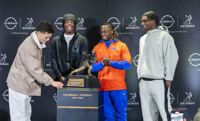 Heisman Trophy finalists, from left, Oregon's Dillon Gabriel, Colorado's Travis Hunter, Boise State's Ashton Jeanty and Miami's Cam Ward pose with the trophy during a college football media availability, Friday, Dec. 13, 2024, in New York. (AP Photo/Corey Sipkin)