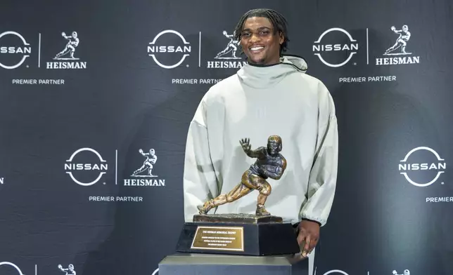 Heisman Trophy finalist Cam Ward,of Miami, poses with the trophy during a college football media availability, Friday, Dec. 13, 2024, in New York. (AP Photo/Corey Sipkin)