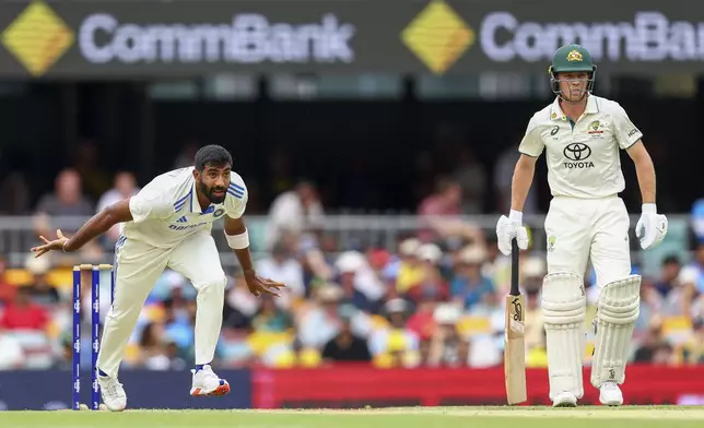 India's Jasprit Bumrah, left, bowls a delivery as Australia's Nathan McSweeney watches from the non-strikers end during play on day one of the third cricket test between India and Australia at the Gabba in Brisbane, Australia, Saturday, Dec. 14, 2024. (AP Photo/Pat Hoelscher)