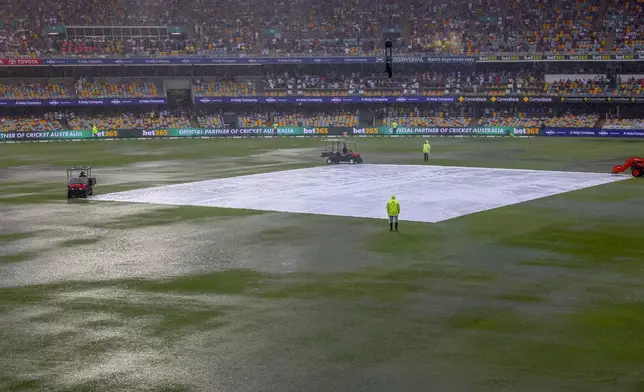 General view of covers on the pitch as it rain during play on day one of the third cricket test between India and Australia at the Gabba in Brisbane, Australia, Saturday, Dec. 14, 2024. (AP Photo/Pat Hoelscher)