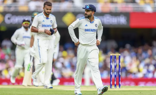 India's Virat Kohli, right, walks back to his fielding position during play on day one of the third cricket test between India and Australia at the Gabba in Brisbane, Australia, Saturday, Dec. 14, 2024. (AP Photo/Pat Hoelscher)