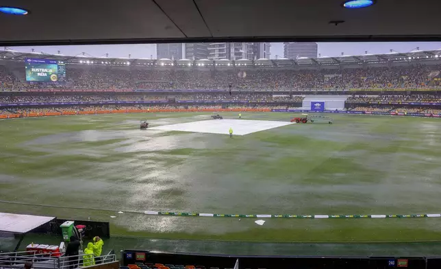 General view of covers on the pitch as it rain during play on day one of the third cricket test between India and Australia at the Gabba in Brisbane, Australia, Saturday, Dec. 14, 2024. (AP Photo/Pat Hoelscher)