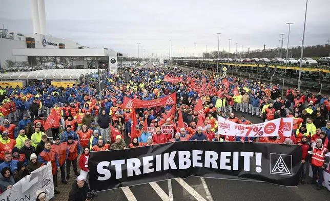 Volkswagen workers march holding a sign with writing reading in German "Ready to Strike!" on the first day of a nationwide warning Volkswagen workers' strike, in Zwickau, Germany, Monday, Dec. 2, 2024. (Hendrik Schmidt/dpa via AP)