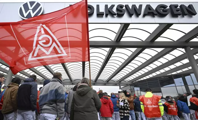 Volkswagen workers wave trade union flags as they demonstrate on the first day of a nationwide warning Volkswagen workers' strike, outside a Volkswagen plant in Zwickau, Germany, Monday, Dec. 2, 2024. (Hendrik Schmidt/dpa via AP)