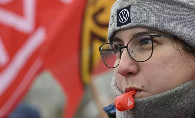 A Volkswagen worker blows a whistle on the first day of a nationwide warning Volkswagen workers' strike, outside a Volkswagen plant in Zwickau, Germany, Monday, Dec. 2, 2024. (Hendrik Schmidt/dpa via AP)