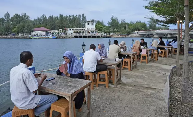 People sit at a cafe on the waterfront near Ulhee Lheue beach, one of the areas hardest his by the Indian Ocean tsunami in 2004, in Banda Aceh, Indonesia, Saturday, Dec 14, 2024. (AP Photo/Achmad Ibrahim)