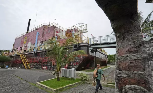 A man walks past a steel barge housing a diesel power generator swept ashore by the Indian Ocean tsunami in 2004 which is now preserved as a monument, in Banda Aceh, Indonesia, Saturday, Dec 14, Dec. 15, 2024. (AP Photo/Achmad Ibrahim)