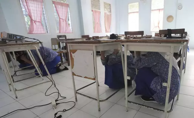 Students take cover under their desks during an earthquake drill at a school in Banda Aceh, Indonesia, Thursday, Dec. 12, 2024. (AP Photo/Achmad Ibrahim)