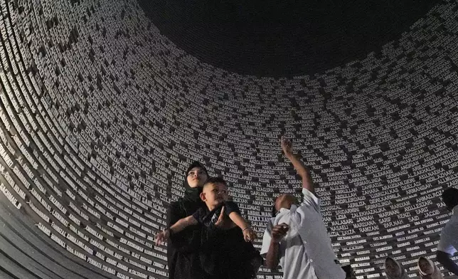 Visitors looks at a wall displaying the names of the victims of 2004 Indian Ocean tsunami, at the Tsunami Museum in Banda Aceh, Aceh province, Indonesia, Saturday, Dec 14, 2024. (AP Photo/Achmad Ibrahim)