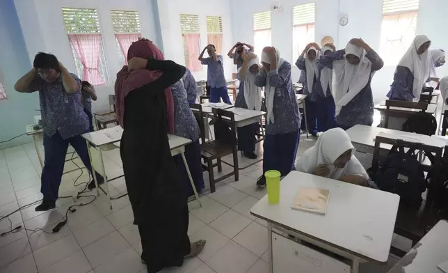 Students take part in an earthquake drill at a school in Banda Aceh, Indonesia, Thursday, Dec. 12, 2024. (AP Photo/Achmad Ibrahim)