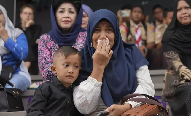 Muslina, a 43-year-old civil servant who is also a tsunami survivor weeps as she and her son Zayyan Firdaus Akmal watch a stage performance depicting the Indian Ocean tsunami in 2004, in Banda Aceh, Indonesia, Saturday, Dec 14, 2024. (AP Photo/Achmad Ibrahim)