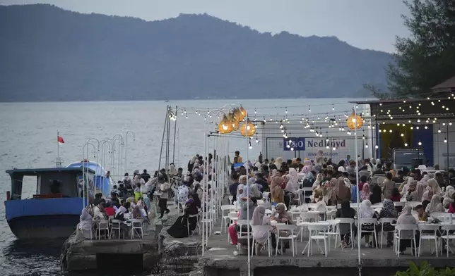 People sit at a coffee shop on the waterfront near Ulee Lheue beach that was one of the areas hardest hit by Indian Ocean tsunami in 2004, in Banda Aceh, Aceh Province, Indonesia, Saturday, Dec. 14, 2024. (AP Photo/Achmad Ibrahim)