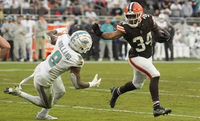 Cleveland Browns running back Jerome Ford (34) runs as Miami Dolphins safety Jevon Holland (8) defends during the first half of an NFL football game Sunday, Dec. 29, 2024, in Cleveland. (AP Photo/Sue Ogrocki)