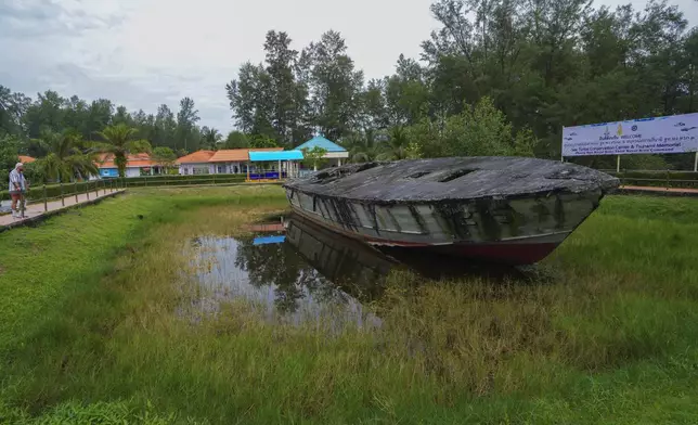 A visitor looks at coastal reconnaissance boat T215 at Tsunami memorial in Phang Nga Naval Base province, southern Thailand, Tuesday, Dec. 10, 2024. (AP Photo/Sakchai Lalit)