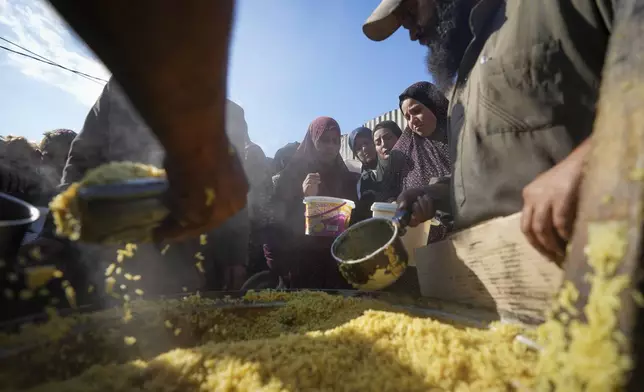 Palestinian women wait to receive food at a distribution center in Deir al-Balah, Gaza Strip, Tuesday, Dec. 17, 2024. (AP Photo/Abdel Kareem Hana)