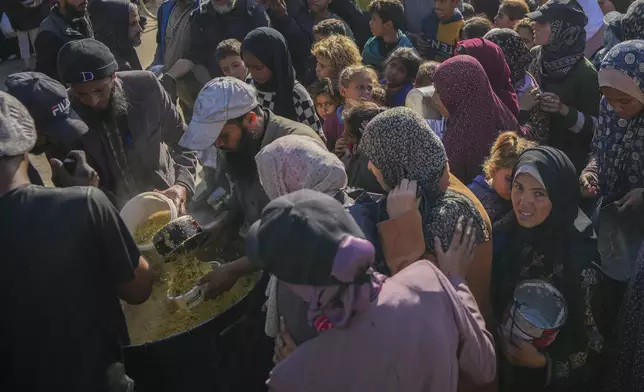 Palestinians gather to get donated food at a distribution center in Deir al-Balah, Gaza Strip, Tuesday, Dec. 17, 2024. (AP Photo/Abdel Kareem Hana)