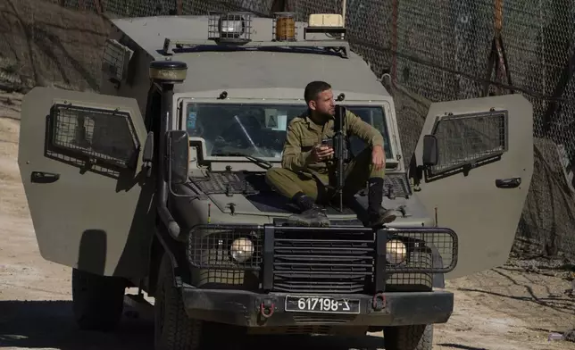 An Israeli soldier sits on an armoured vehicle next to security fence near the so-called Alpha Line that separates the Israeli-controlled Golan Heights from Syria, in the town of Majdal Shams, Wednesday, Dec. 18, 2024. (AP Photo/Matias Delacroix)