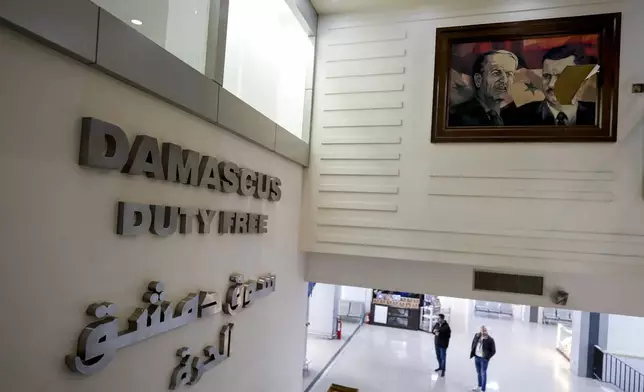 A torn picture of ousted Syrian President Bashar Assad, right, and his late father, President Hafez Assad, is seen attached at the Duty Free of the Damascus airport, Syria, Wednesday, Dec. 18, 2024. (AP Photo/Omar Sanadiki)