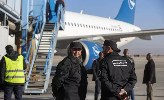 General Security personnel stand next to a Syrian Air airplane ahead of take-off as the airport reopens for internal flights in Damascus, Syria, Wednesday, Dec. 18, 2024. (AP Photo/Omar Sanadiki)