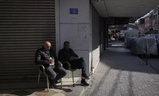 Palestinians sit in front of closed shops during a general strike called as Palestinian security forces mount a major raid against militants in the Jenin refugee camp in the Israeli-occupied West Bank, Monday, Dec. 23, 2024. (AP Photo/Majdi Mohammed)