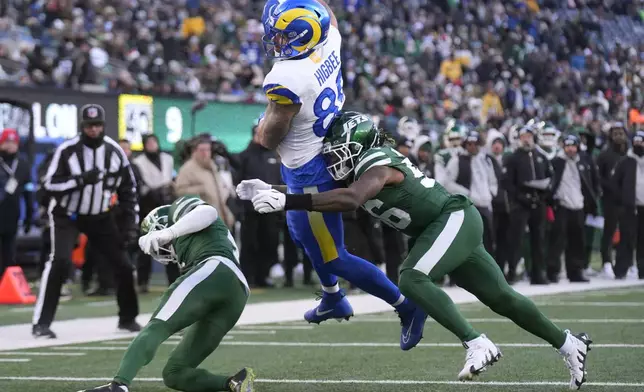 CORRECTS PLAYER TO TYLER HIGBEE - Los Angeles Rams tight end Tyler Higbee, middle, jumps toward the end zone past New York Jets cornerback D.J. Reed, left, and linebacker Quincy Williams to score during the second half of an NFL football game in East Rutherford, N.J., Sunday, Dec. 22, 2024. (AP Photo/Seth Wenig)