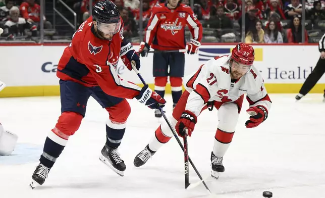 Washington Capitals defenseman Matt Roy (3) and Carolina Hurricanes center Tyson Jost (27) battle for the puck during the second period of an NHL hockey game, Friday, Dec. 20, 2024, in Washington. (AP Photo/Nick Wass)