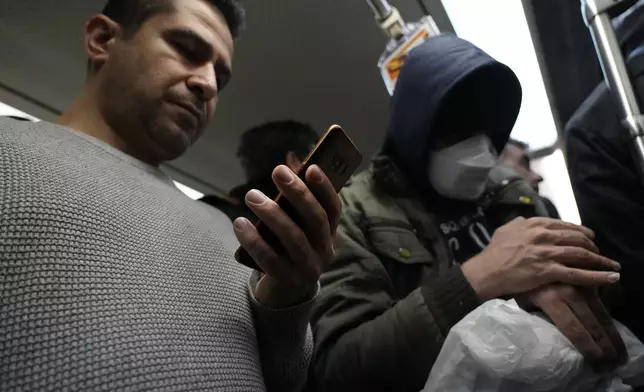 A man uses his smartphone while riding the subway in Tehran, Iran, Tuesday, Dec. 24, 2024. (AP Photo/Vahid Salemi)