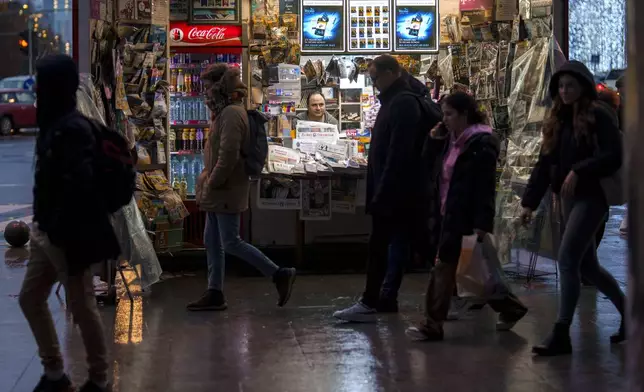 People walk by a newspaper stand after the Constitutional Court annulled the first round of the country's presidential election, days after allegations that Russia ran a coordinated online campaign to promote Calin Georgescu a far-right outsider who won the first round, in Bucharest, Romania, Friday, Dec. 6, 2024. (AP Photo/Vadim Ghirda)